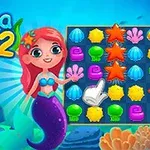 Syrenka z czerwoną fryzurą wskazująca na planszę z kolorowymi ikonami pod wodą, na tle z napisem Aqua Blitz 2