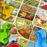 Plansza z kolorowymi pionkami w kształcie kaczek i numerowanymi polami z ilustracjami zwierząt i roślin