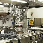 Profesjonalna kuchnia restauracyjna z wiszącymi przyborami kuchennymi i stalowymi blatami