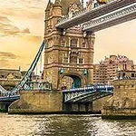 Tower Bridge w Londynie o zachodzie słońca, z widocznymi wieżami i fragmentem mostu, oraz zabudowania w tle