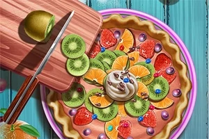 Tarta z różnorodnymi owocami, takimi jak kiwi, pomarańcze i truskawki, ozdobiona bitą śmietaną i kolorowymi dekoracjami na talerzu, z deseczką do krojenia i nożem po lewej stronie