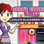 Kobieta z czerwonymi włosami w kuchni, ubrana w fioletową bluzkę, trzyma kciuk w górę obok napisu Saras Cooking Class